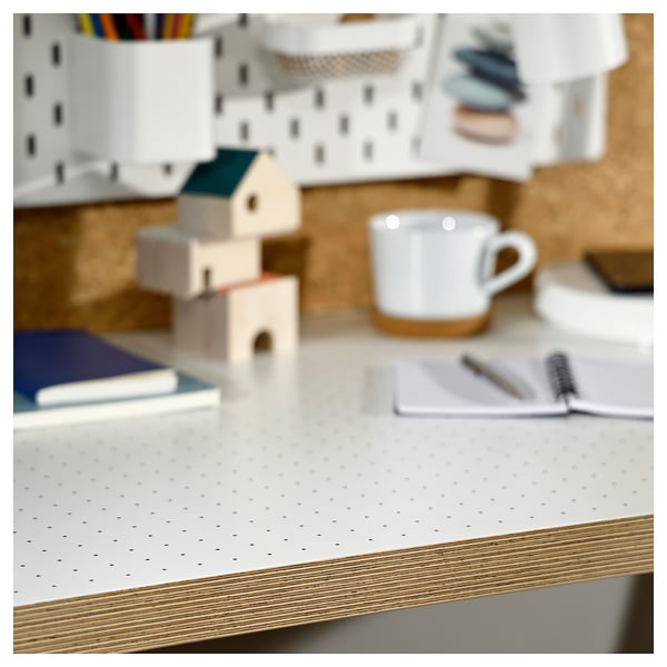 Bureau met wit geperforeerd blad, lichte houten randen en een eenvoudig ontwerp. Inclusief een witte mok, een notitieboekje en speelgoedhuisjes.