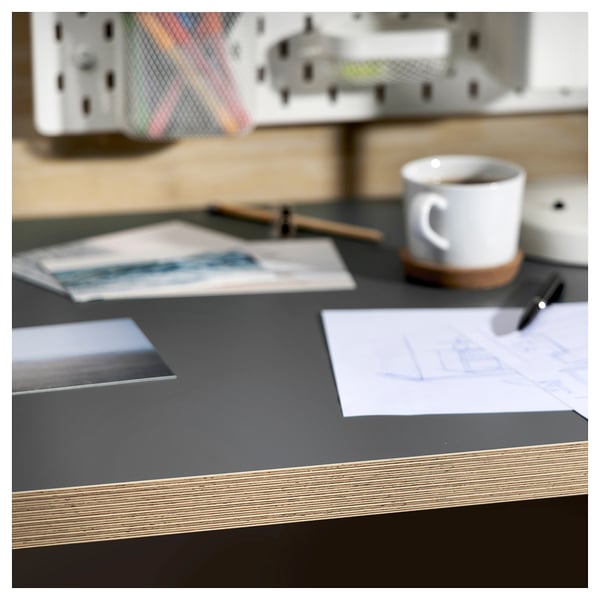 Bureau met zwart tafelblad, witte mok, papieren en pen.