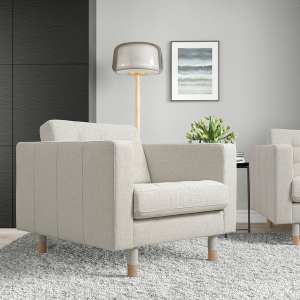 Minimalistische woonkamer: 2 grijze fauteuils, lamp, vloerkleed, zeegezicht.