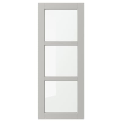 Een grijze LERHYTTAN kastdeur met een massief houten frame en afgeschuinde randen, met drie heldere glazen panelen in een rechthoekige lay-out.