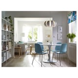 Moderne eethoek met blauwe LIDÅS-stoelen, witte tafel, lamp, planten en daglicht.