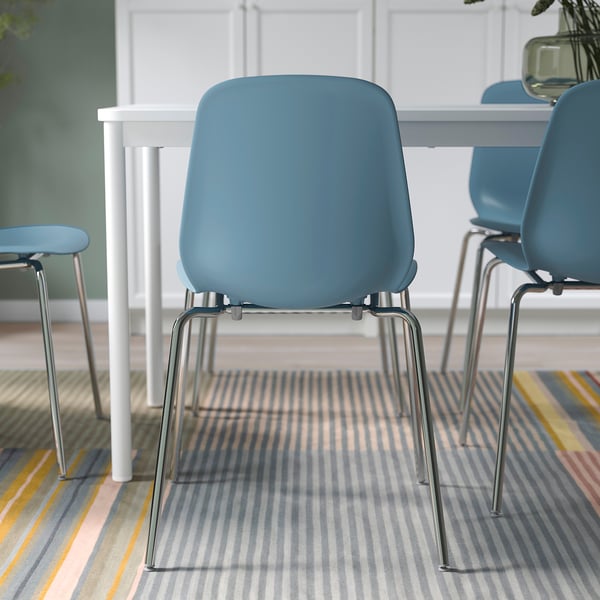 Blauwe stoelen met chromen poten rond een witte tafel, geschikt om te stapelen en makkelijk schoon te maken.