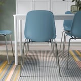 Blauwe stoelen met chromen poten rond een witte tafel, geschikt om te stapelen en makkelijk schoon te maken.