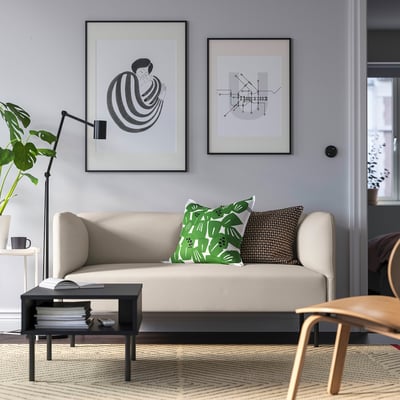 Fokus: LILLEHEM beige modulaire bank, grijze muur, groene kussens, zwarte salontafel, houten stoel, moderne kunstprints.