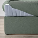 Close-up van LILLFJÄLLET boxspringbedden schuin hoofdeinde met extra kussens voor comfort en geïntegreerde opbergruimte onder het bed.