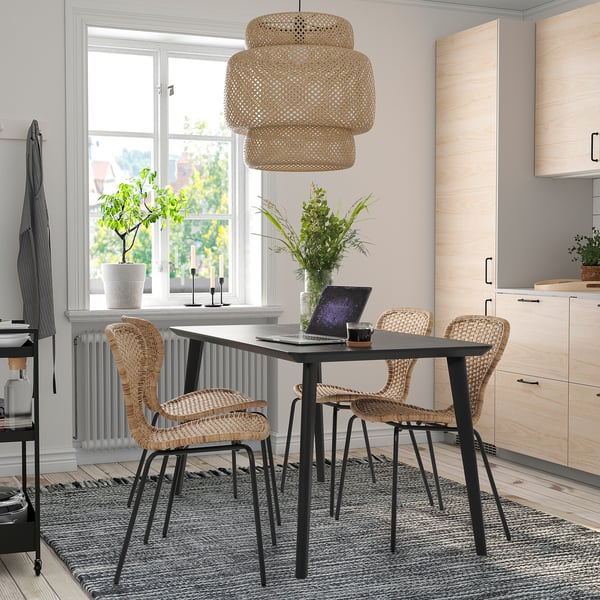 Gezellige LISABO eetopstelling met zwarte tafel, natuurlijke stoelen, hanglamp en planten.