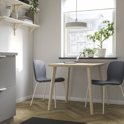 Moderne eethoek met heldere houten tafel en grijze stoelen. Compact en gezellig, ideaal voor kleine ruimtes.