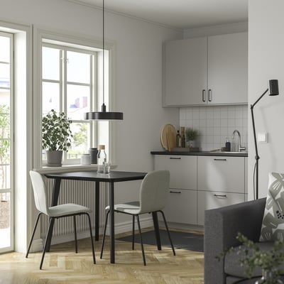 Moderne eethoek met zwarte tafel, grijze stoelen en hanglamp, perfect voor compacte ruimtes.