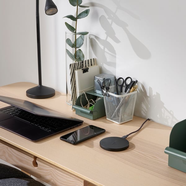 Houten bureau met lichtlamp, groene plant, laptop, telefoon, LIVBOJ zwarte draadloze oplader, grijze mesh briefpapierhouder.