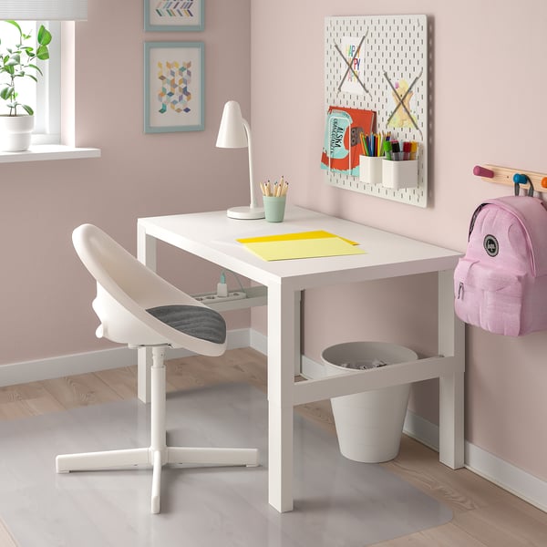 Eenvoudige opstelling van een wit kinderbureau. Klein wit bureau met stoel, prullenbak, lamp en wanddecoraties.
