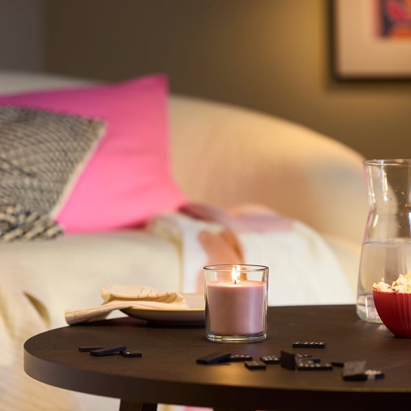 Gezellige slaapkamer met een brandende roze kaars, afstandsbediening, popcorn voor filmavond.