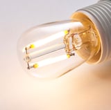 Close-up van een energiezuinige LUNNOM led-lamp, met zijn warme gloed en helder glazen ontwerp.