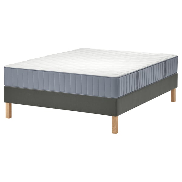 Een lyngor bed met een grijze matras en platform, met houten poten en een gewatteerd ontwerp.