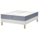 Een witte LYNGÖR bedbodem met lichtgrijze vågstranda matras, met houten poten en een gewatteerde top.