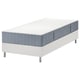 Een wit LYNGÖR bed met een opgerold blauwgrijs matras, voorzien van pocketveren voor comfort en ondersteuning.