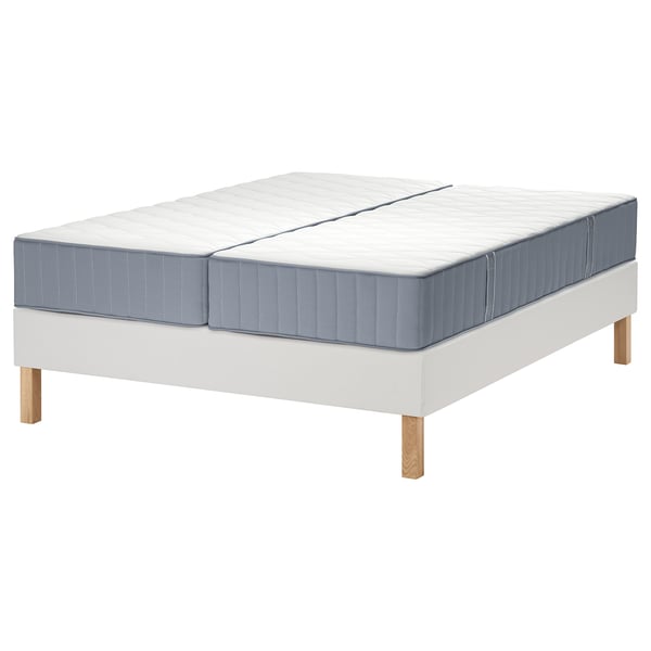 Een witte LYNGÖR bedbodem met een blauwgrijze vågstranda matras, voorzien van een uniek pocketverensysteem voor comfort en ondersteuning.