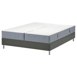 Afbeelding toont een gespleten, tweekleurige kingsize matras op een donkergrijze platformbodem. De basis heeft metalen poten en een eenvoudig ontwerp.