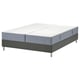 Afbeelding toont een gespleten, tweekleurige kingsize matras op een donkergrijze platformbodem. De basis heeft metalen poten en een eenvoudig ontwerp.