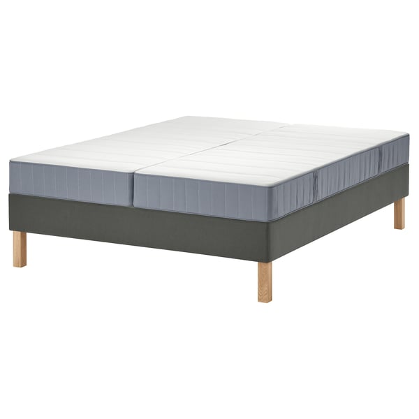 Een modern LYNGÖR bed met een witte matras en grijze bodem. De basis heeft houten poten en de matras heeft pocketveren voor comfort.