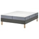 Een modern LYNGÖR bed met een witte matras en grijze bodem. De basis heeft houten poten en de matras heeft pocketveren voor comfort.