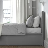 Modern bed met grijs hoofdeinde, lades, led-verlichting, strak design.