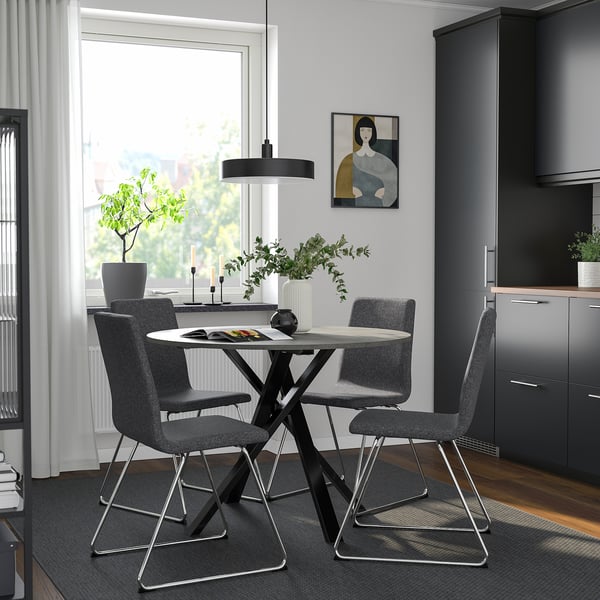 Moderne eethoek met ronde tafel en grijze stoelen, strakke poten, polyester bekleding, gezellige keukenhoek met kunst en planten.