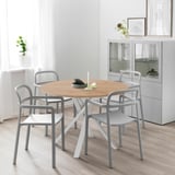 Ronde eettafel met 4 grijze stoelen in lichte, minimalistische kamer.