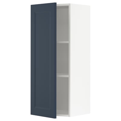Een METOD keukenkast met een open blauwe deur, met een modern traditioneel design in donkerblauw en wit.