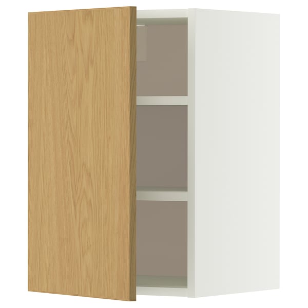 Een open witte METOD wandkast met een licht eikenhouten deur, met daarin twee legplanken.