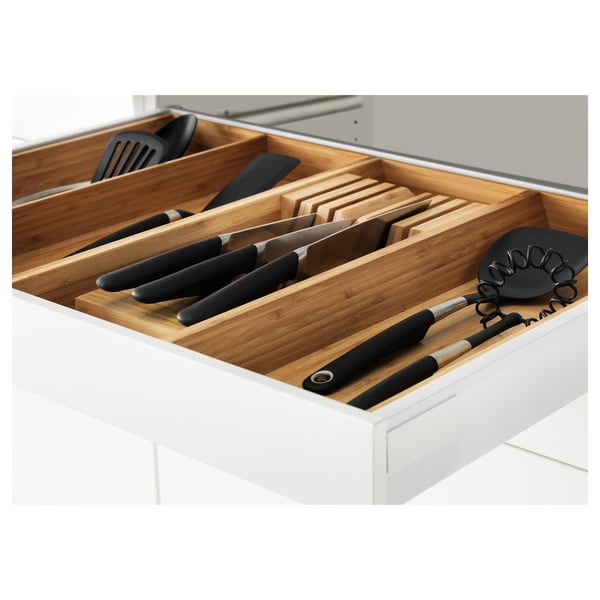 Houten lade-organizer gevuld met messen, keukengerei in een witte lade.