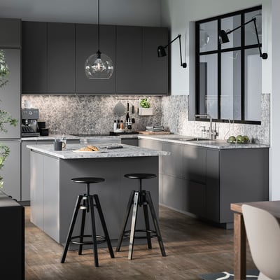 Moderne keuken met MITTLED zwarte hanglampen, grijze kasten, marmeren aanrechtblad en twee hoge krukken.