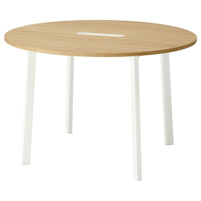 Een ronde vergadertafel met licht houten blad en witte poten. Modern, minimalistisch, ideaal voor kleine groepen. Lade voor kabelbeheer.