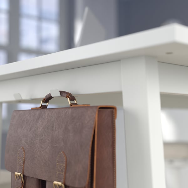 Bruine leren aktetas hangt aan witte haken aan een hoge tafel, perfect voor snelle gesprekken of werk onderweg in de lobby.