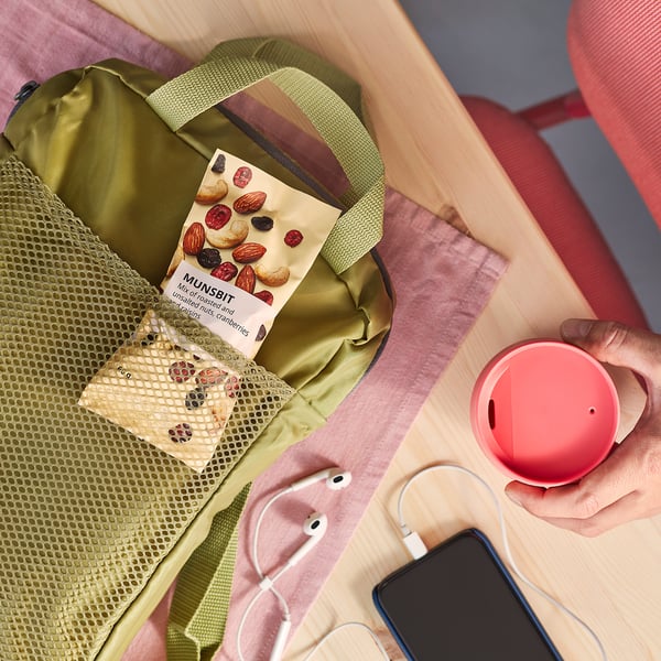 Persoon met rood geval, groene rugzak, snacks, telefoon, oortelefoons, MUNSBIT-voedsel.