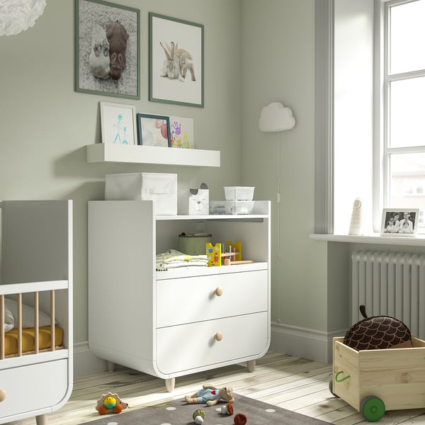Kinderkamer met MYLLRA dressoir, wieg, speelgoed, groene muren, vloerkleed, lamp.