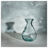 Een MYRMOSAIK glazen vaas, groenachtig blauw van kleur, met een organische, handgemaakte vorm, gemaakt van gerecycled glas.