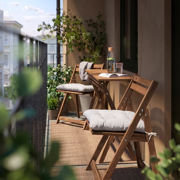 Klein balkon met NÄMMARÖ houten tafel en stoelen, stoelen met kussens, buitenomgeving.