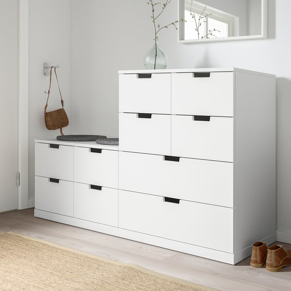 Moderne witte NORDLI kisten, smal en hoog, gemaakt van spaanplaat en vezelplaat, passen netjes naast een eettafel of console.