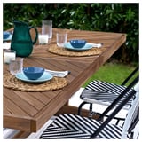 Buiten dineren opstelling met norrmanso houten tafel, rieten stoelen, blauwe kommen, glazen en groene pitcher.