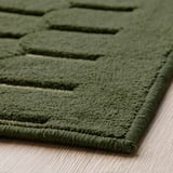 Groen gedessineerd tapijt, gestructureerd oppervlak op houten vloer.