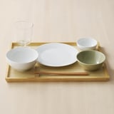 Bamboe dienblad met kom, bord, kleine kommen, eetstokjes en glas, ideaal voor het serveren van maaltijden.