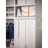 Een witte parkla opbergkoffer, rechthoekig, met beddengoed. Het is semi-transparant en gestapeld op een plank, netjes passend naast andere items.