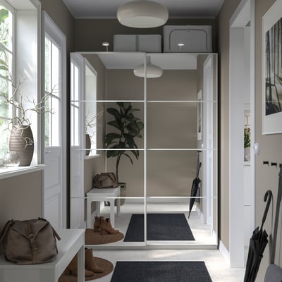 Moderne entree met PAX kledingkast, schuifdeuren, grijs vloerkleed, laarzen, tas en potplant.