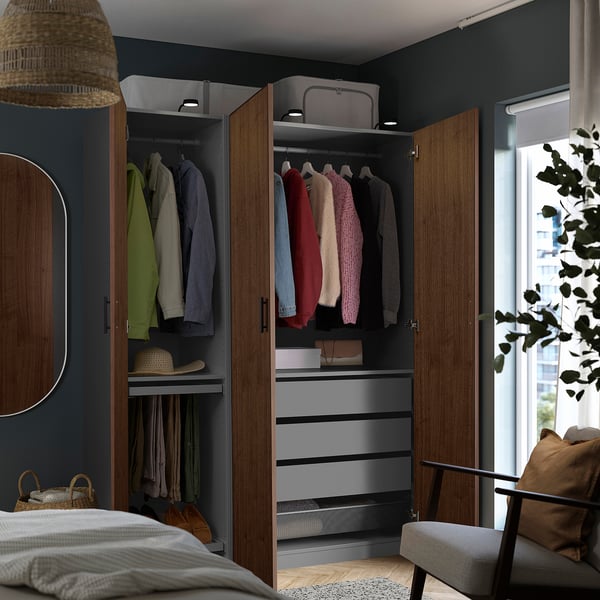 Een moderne slaapkamer met een inloopkast met kleding, planken en lades in houten kasten met donker walnootfineer.