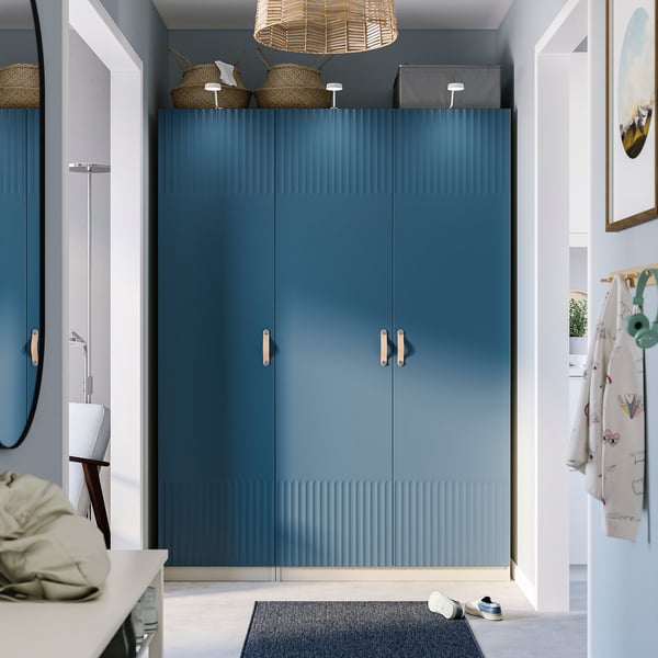 Moderne entree met blauwe PAX-kledingkast, getextureerde deuren, rieten manden, geweven licht, schoenenrek, haken.