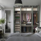 Moderne slaapkamer met PAX kledingkast, kleding, planken, verlichting, bed en plant.