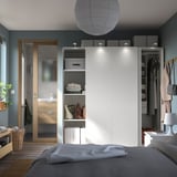 Moderne slaapkamer met witte PAX kledingkast, schuifdeuren, grijs bed, houten vloer, blauwgroene wanden en hangende decoraties.