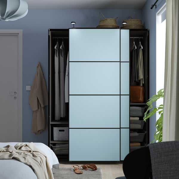 Moderne blauwe kledingkast met schuifdeuren, het opbergen van kleding en accessoires, gepositioneerd tegen een blauwgrijze muur in een slaapkamer.