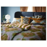 Slaapkamer met tropisch thema met blauwe bank, palmbeddengoed, lamp en plant.