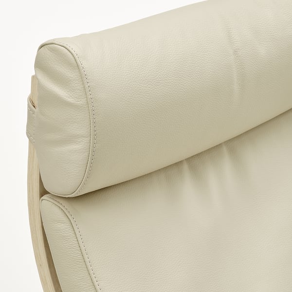 Close-up van de gecapitonneerde hoofdsteun van poang-stoelen, met glad, hoogwaardig crèmekleurig leer met nette stiksels.